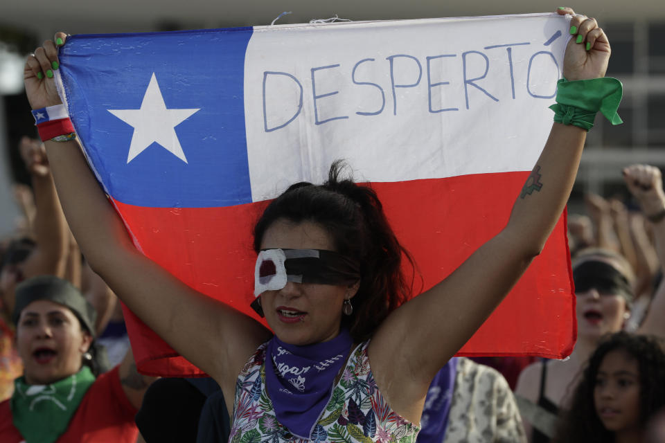 Liss Fernandez holds up a Chilean flag as she performs the feminist anthem "A rapist in your path," in a demonstration against gender-based violence, in front of the Supreme Court, in Brasilia, Brazil, Friday, Dec. 13, 2019. (AP Photo/Eraldo Peres)