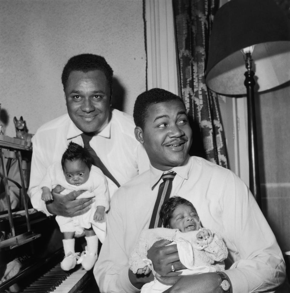 Popular Jamaican singing duo Vic Evans (left) and Chester Harriott with their babies, which were born within a week of each other, 27th May 1955. Evans is holding his daughter Angela and Harriott his son, Chester Jnr. Harriot is also the father of celebrity chef Ainsley Harriot (Photo by Fred Morley/Fox Photos/Hulton Archive/Getty Images)