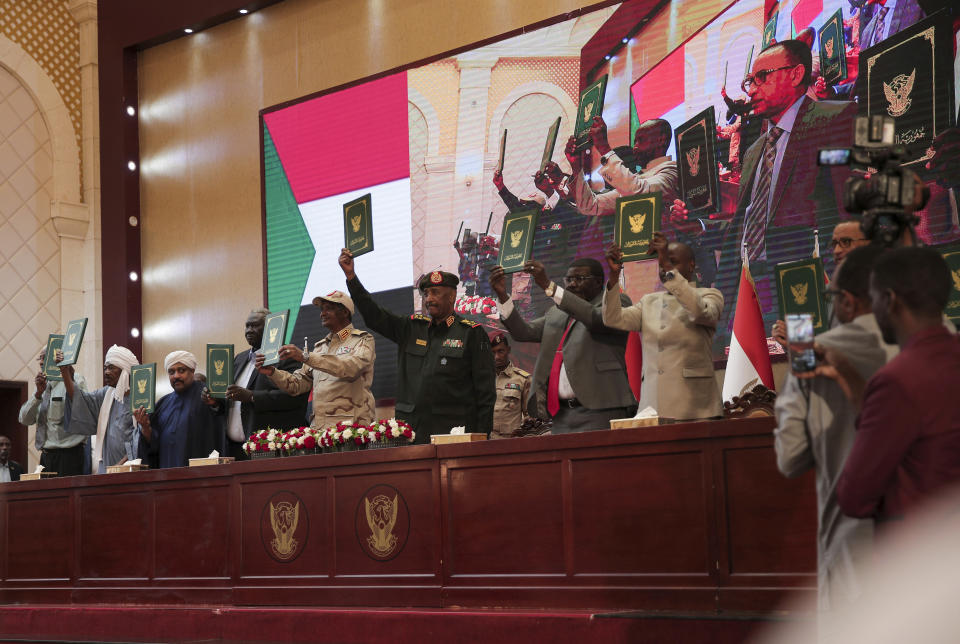 Sudan's Army chief Gen. Abdel-Fattah Burhan, center, and others hold a document following the signature of an initial deal aimed at ending a deep crisis caused by last year's military coup, in Khartoum, Sudan, Monday, Dec. 5, 2022. Sudan’s coup leaders and the main pro-democracy group signed a deal to establish a civilian-led transitional government following the military takeover last year. But key players refused to participate, and no deadline was set for the transition to begin. (AP Photo/Marwan)