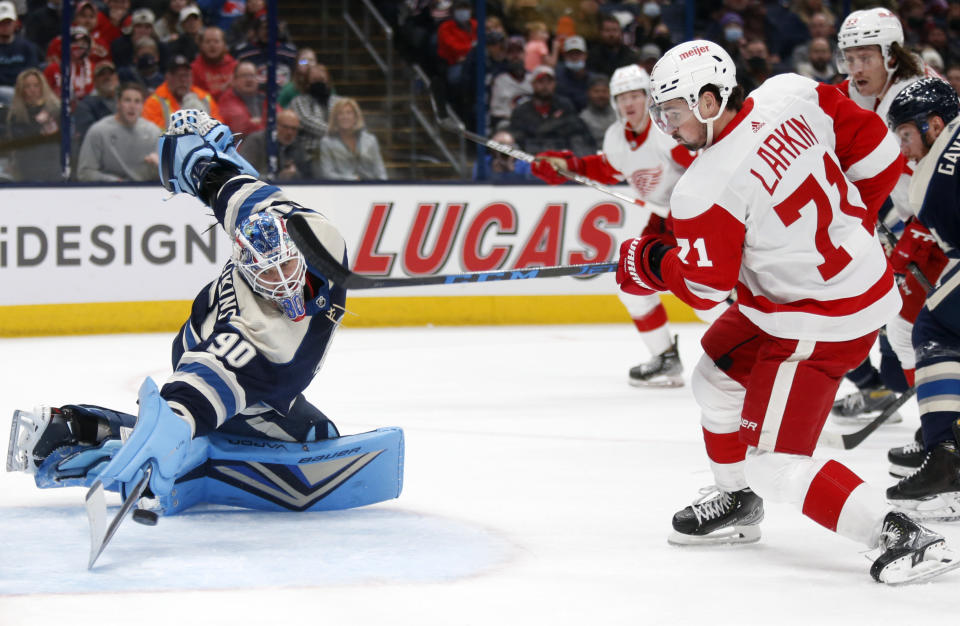Detroit Red Wings forward Dylan Larkin, front right, scores a goal past Columbus Blue Jackets goalie Elvis Merzlikins during the first period of an NHL hockey game in Columbus, Ohio, Monday, Nov. 15, 2021. (AP Photo/Paul Vernon)