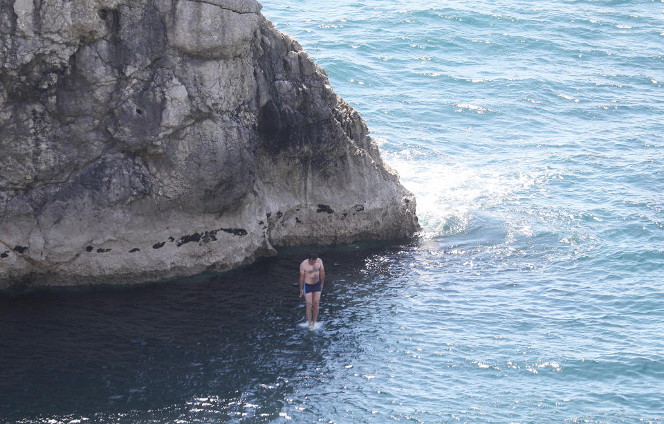 A person jumps into the sea from Durdle Door, near Lulworth, despite Dorset Council announcing that the beach was closed to the public after three people were seriously injured jumping off cliffs into the sea.