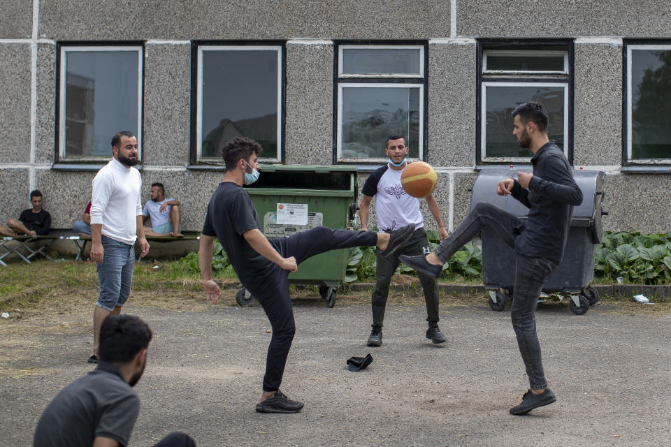 Migrants from Iraq, play with ball at the refugee camp in the village of Verebiejai, some 145km (99,1 miles) south from Vilnius, Lithuania, Sunday, July 11, 2021. Migrants at the school in the village of Verebiejai, about 140 kilometers (87 miles) from Vilnius, haven't been allowed to leave the premises and are under close police surveillance. Some have tested positive for COVID-19 and have been isolated in the building. (AP Photo/Mindaugas Kulbis)