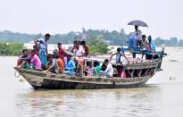 Indian villagers cross a flooded area by a boat, at Jhargaon in Morigaon district of Assam. (Photo credit should read Anuwar Ali Hazarika/Barcroft Media via Getty Images)