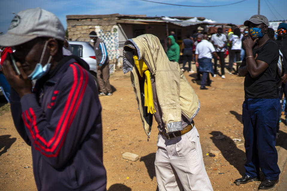 People line up to receive food handouts in the Olievenhoutbos township of Midrand, South Africa, Saturday May 2, 2020. though South Africa begun a phased easing of its strict lockdown measures on May 1, its confirmed cases of coronavirus continue to increase. (AP Photo/Jerome Delay)