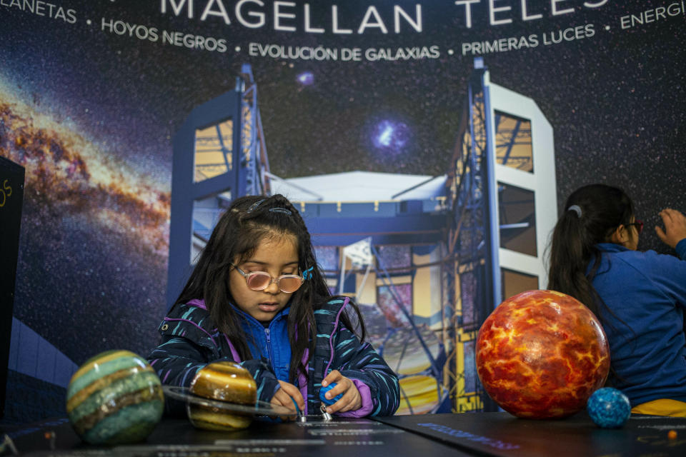 A blind child interacts with a representation of the solar system during sensorial experience with tools created by NASA and Edinburgh University to experience an eclipse, at the Helen Keller school in Santiago, Chile, Tuesday, June 25, 2019. The event comes exactly one week ahead of a total solar eclipse which is set to be fully visible in various South American countries, including Chile. (AP Photo/Esteban Felix)