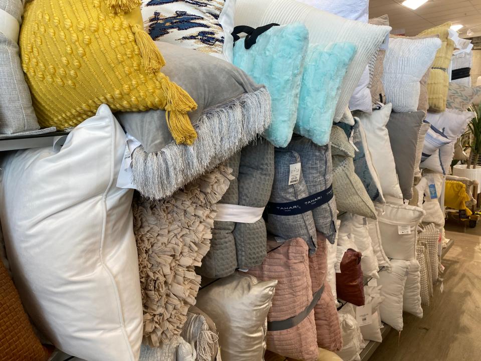 gray, yellow, and blue pillows stuffed onto shelves in a homegoods