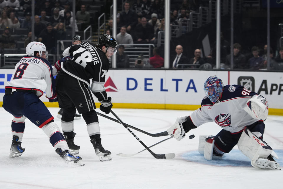 Los Angeles Kings right wing Alex Laferriere, second from left, shoots the puck against Columbus Blue Jackets goaltender Elvis Merzlikins, while defenseman Zach Werenski defends during the second period of an NHL hockey game Tuesday, Feb. 20, 2024, in Los Angeles. (AP Photo/Ryan Sun)
