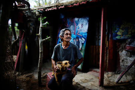 Artist Remigio Hernandez, 64, sits with his dog at his self made "Museum of Baby" at his home in Moron, Cuba, February 16, 2017. Picture taken February 16, 2017. REUTERS/Alexandre Meneghini