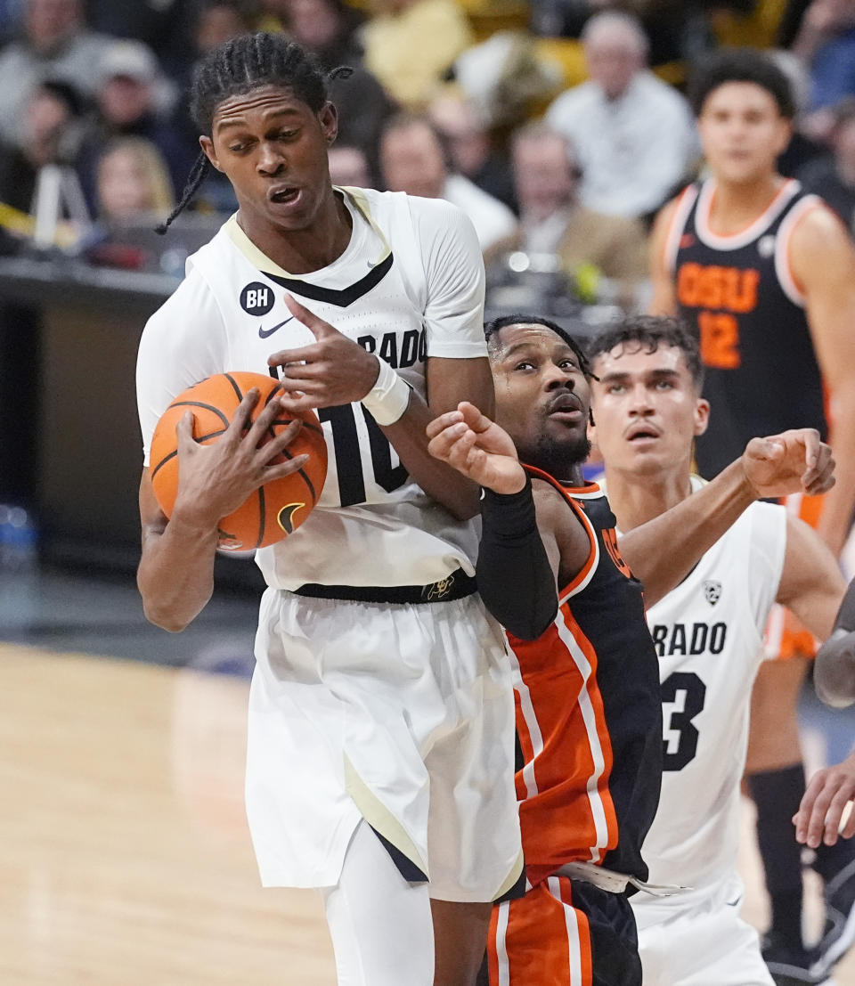 Colorado forward Cody Williams, left, pulls in a rebound as Oregon State guard Dexter Akanno, front right, defends in the first half of an NCAA college basketball game Saturday, Jan. 20, 2024, in Boulder, Colo. (AP Photo/David Zalubowski)