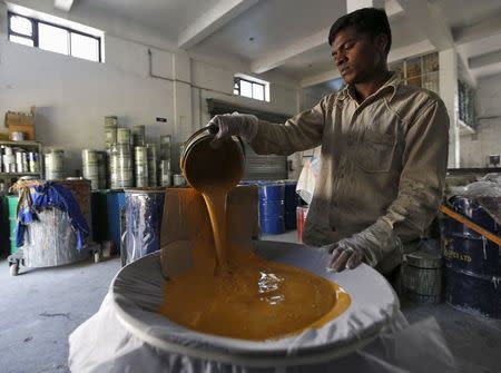 A worker filters paint using a piece of cloth inside a Reliable Paints factory at an industrial area on the outskirts of Vadodara in Gujarat, India, November 5, 2015. REUTERS/Amit Dave