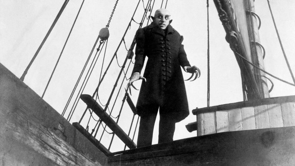 a vampirelike creature stands on the deck of a ship ini a scene from nosferatu, a good housekeeping pick for best halloween movies