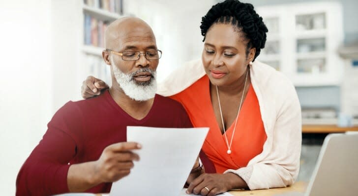 Image shows a couple looking over their retirement investments. T. Rowe Price says investors should expect returns in the coming period that will be lower than recent years. 