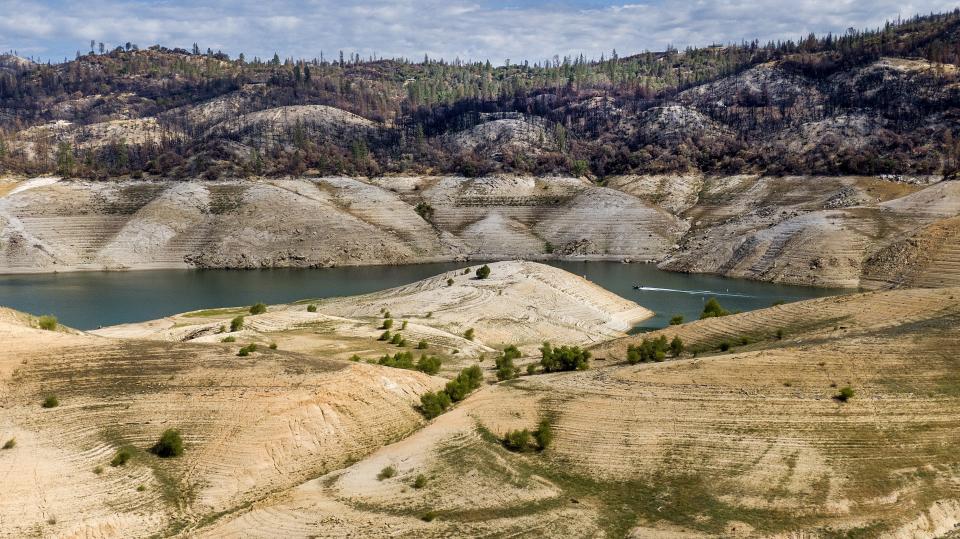 FILE - A boat crosses Lake Oroville below trees scorched in the 2020 North Complex Fire on May 23, 2021, in Oroville, Calif. Months of winter storms have replenished California's key reservoirs after three years of punishing drought. (AP Photo/Noah Berger, File)