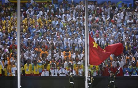 A paramilitary police officer raises the Chinese national flag out in a flag-raising ceremony during the 2014 Nanjing Youth Olympic Games opening ceremony, in Nanjing, Jiangsu province, August 16, 2014. REUTERS/Aly Song