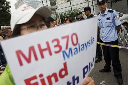 A woman whose relative was aboard Malaysia Airlines flight MH370 holds placard after police stopped protesting relatives from entering a road leading to the Malaysian embassy in Beijing August 7, 2015. REUTERS/Damir Sagolj/Files