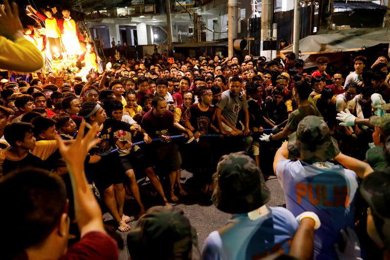 Filipino devotees attempt to get through cops surrounding the carriage of the Black Nazarene during the annual procession