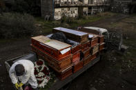 Workers collect the coffins of people that have been recently cremated amid the new coronavirus pandemic, at the La Recoleta cemetery in Santiago, Chile, Sunday, June 28, 2020. The coffins are collected, destroyed, and processed by a company specialized in organic waste. (AP Photo/Esteban Felix)