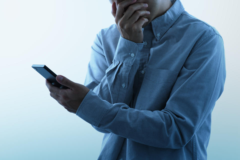 Man looking at a smartphone screen in shock. 