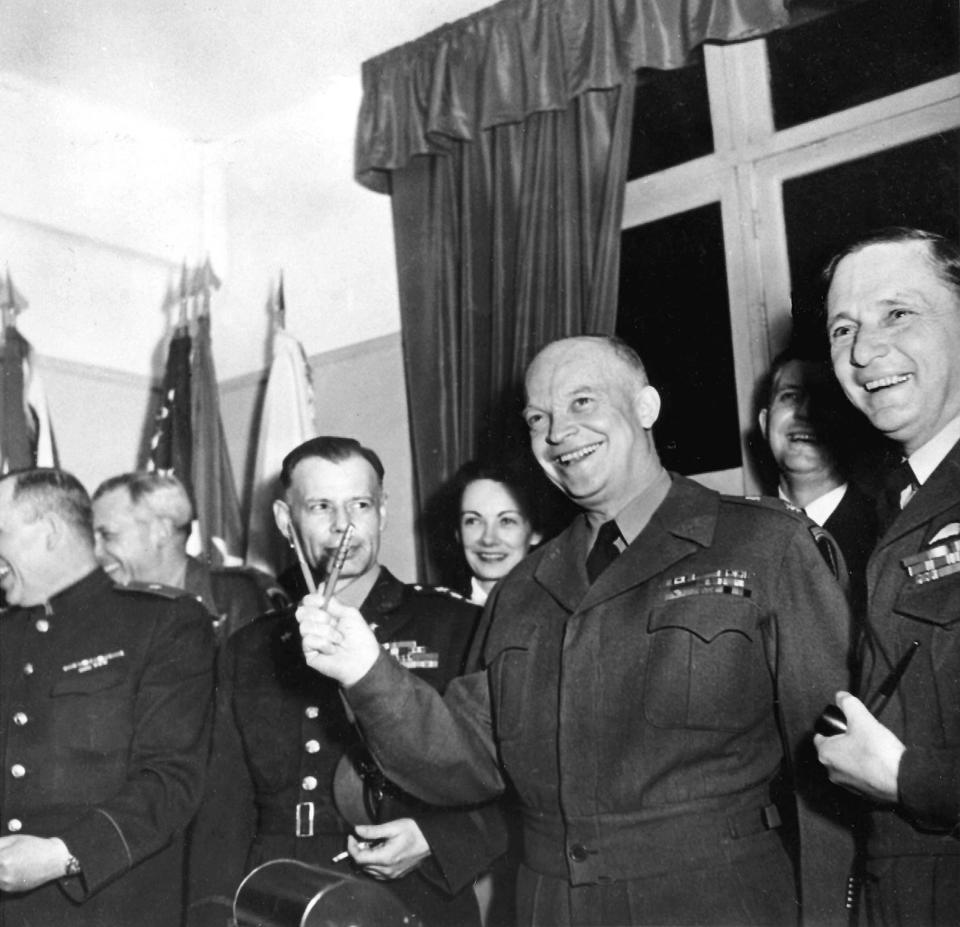 FILE - In this May 7, 1945 file photo Gen. Dwight D. Eisenhower makes a V for Victory with two pens used for the signing of Germany's unconditional surrender at Reims, France. Nazi commanders signed their surrender to Allied forces in a French schoolhouse 75 years ago this week, ending World War II in Europe and the Holocaust. Unlike the mass street celebrations that greeted this momentous news in 1945, surviving veterans are marking V-E Day this year in virus confinement, sharing memories with loved ones, instead of in the company of comrades on public parade. (AP Photo, File)