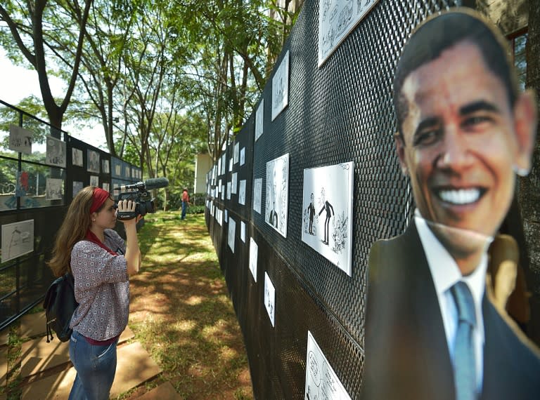 A journalist films at an outdoor exhibition of editorial cartoons and caricatures of US President Barack Obama at PAWA-254 art centre in Nairobi on July 27, 2015