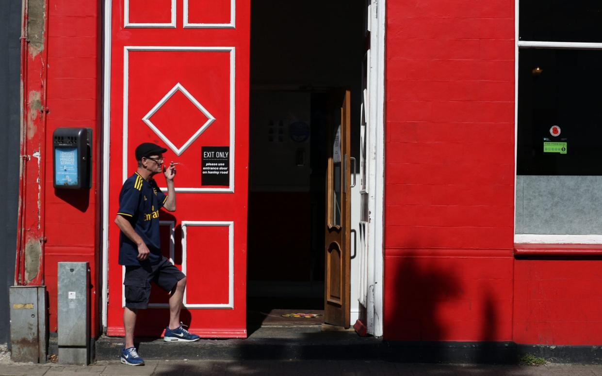 LONDON, ENGLAND - JULY 12: A fan in an Arsenal shirt leaves The Corner Flag pub through an Exit Only door so he can smoke a cigarette during the Premier League match between Tottenham Hotspur and Arsenal FC at on July 12, 2020 in London, United Kingdom. Football Stadiums around Europe remain empty due to the Coronavirus Pandemic as Government social distancing laws prohibit fans inside venues resulting in all fixtures being played behind closed doors. (Photo by Charlotte Wilson/Offside/Offside via Getty Images) - Charlotte Wilson/Offside via Getty Images