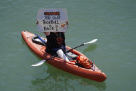 A woman kayaker holds up a sign in McCovey Cove before the start of an opening day baseball game between the San Francisco Giants and the Colorado Rockies, Friday, April 9, 2021, in San Francisco. (AP Photo/Eric Risberg)