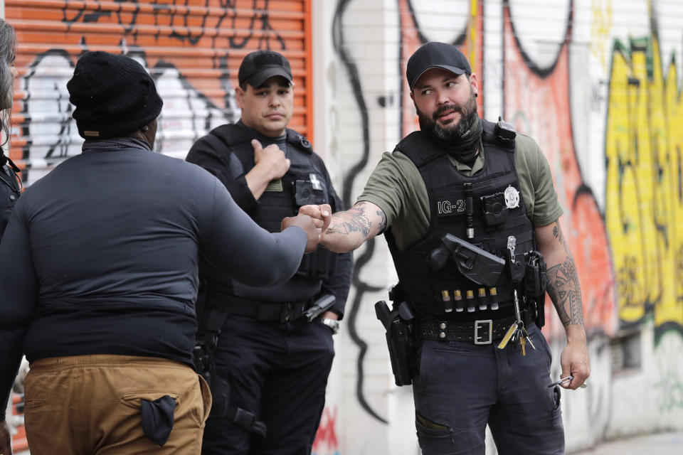 Private security guards working with local businesses greet a protester near the site of a shooting Monday, June 29, 2020, in Seattle, where streets are blocked off in what has been named the Capitol Hill Occupied Protest zone. One man was killed and another wounded early Monday in the protest zone, the second deadly shooting in the area. Police said the shooting happened before dawn in the city's Capitol Hill neighborhood, near downtown. (AP Photo/Elaine Thompson)