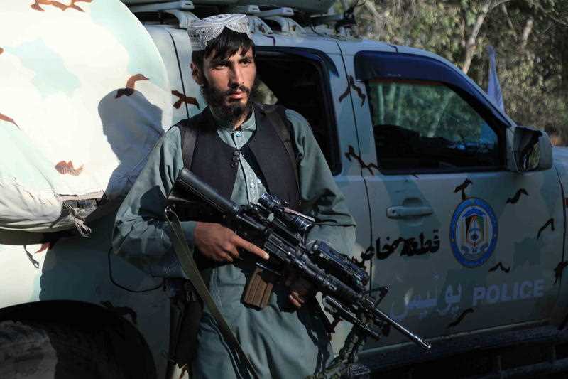 Taliban use a captured Afghan security forces vehicle as they stand guard at a checkpoint as they took control of Herat, Afghanistan.