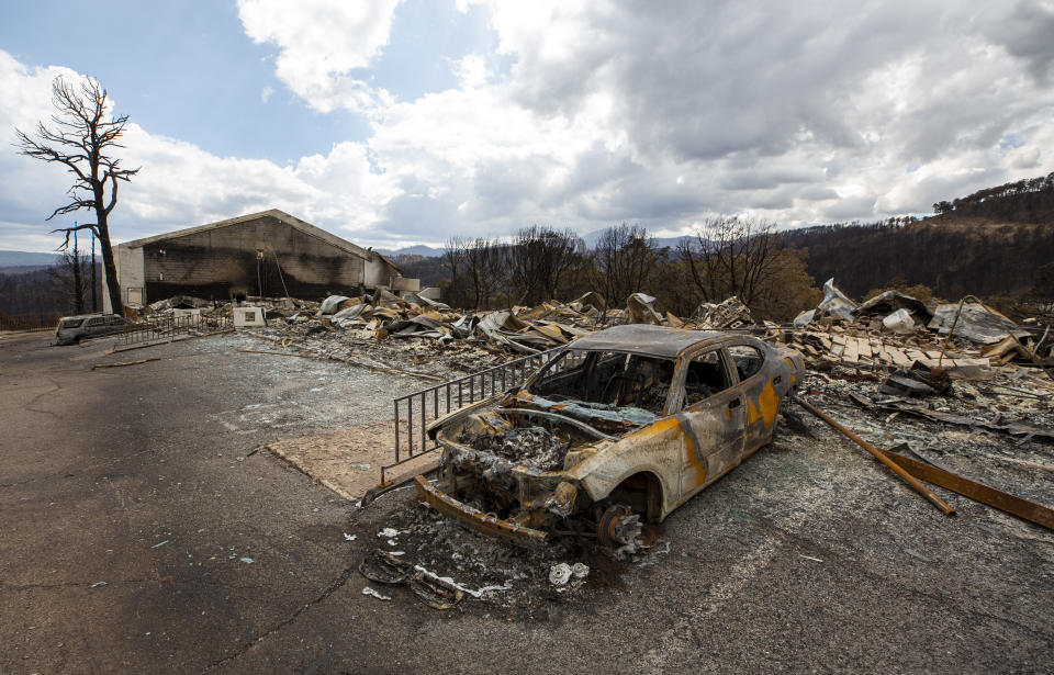 A charred car and the remains of the Swiss Chalet Hotel are pictured after being destroyed by the South Fork Fire in the mountain village of Ruidoso, N.M., Saturday, June 22, 2024. (AP Photo/Andres Leighton)