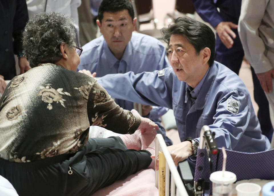 Japan's Prime Minister Shinzo Abe, right, talks with an elderly woman at a shelter as Abe visits the site of a landslide triggered by the Sept. 6, earthquake in Abira, Hokkaido, northern Japan Sunday, Sept. 9, 2018. Japanese authorities say dozens of people have been confirmed dead from a powerful earthquake that struck the northern island of Hokkaido last week. (Kyodo News via AP)