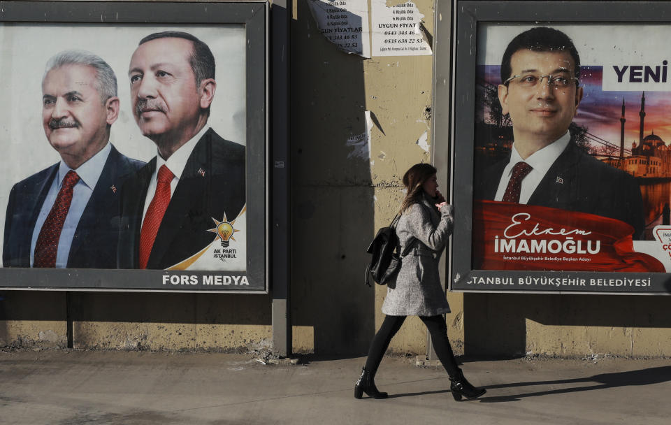 FILE- In this file photo dated March 4, 2019, A woman walks past posters showing Binali Yildirim, left, the mayoral candidate for Istanbul of Turkey's President Recep Tayyip Erdogan's ruling Justice and Development Party's (AKP) and the candidate of Republican People's Party (CHP), Ekrem Imamoglu, right, in Istanbul, ahead of local elections scheduled for March 31. For Turkey's President Recep Tayyip Erdogan, the local elections are not just a vote to decide who should collect the garbage and maintain roads, they are about Turkey's future national "survival." (AP Photo/Emrah Gurel, File)