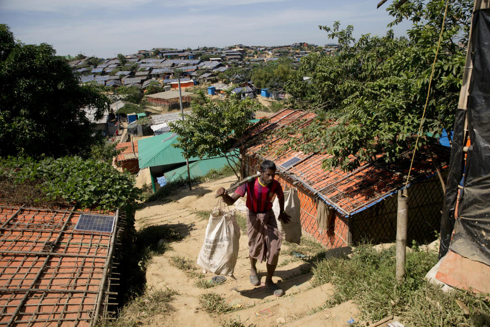 A Rohingya refugee carries plastic sacks filled with food at Jamtoli refugee camp, near Cox's Bazar, in Bangladesh, Thursday, Nov. 15, 2018. The head of Bangladesh's refugee commission said plans to begin a voluntary repatriation of Rohingya Muslim refugees to their native Myanmar on Thursday were scrapped after officials were unable to find anyone who wanted to return. (AP Photo/Dar Yasin)