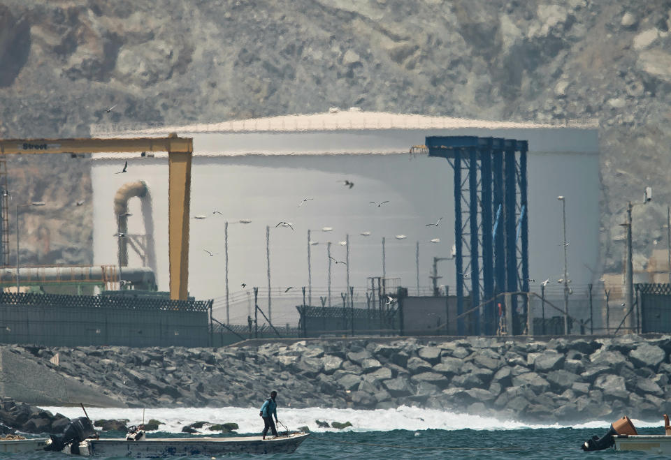 A fisherman prepares his boat near an oil storage tank in Fujairah, United Arab Emirates, Monday, May 13, 2019. Saudi Arabia said Monday two of its oil tankers were sabotaged off the coast of the United Arab Emirates near Fujairah in attacks that caused "significant damage" to the vessels, one of them as it was en route to pick up Saudi oil to take to the United States. (AP Photo/Jon Gambrell)