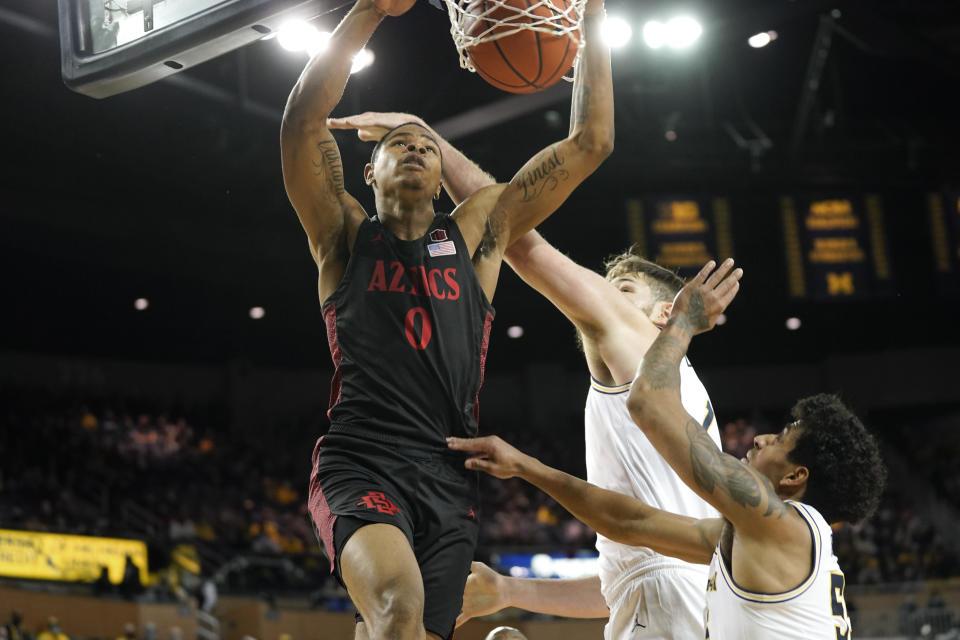San Diego State forward Keshad Johnson (0) dunks on Michigan center Hunter Dickinson (1) and Eli Brooks (55) in the first half of an NCAA college basketball game in Ann Arbor, Mich., Saturday, Dec. 4, 2021. (AP Photo/Paul Sancya)