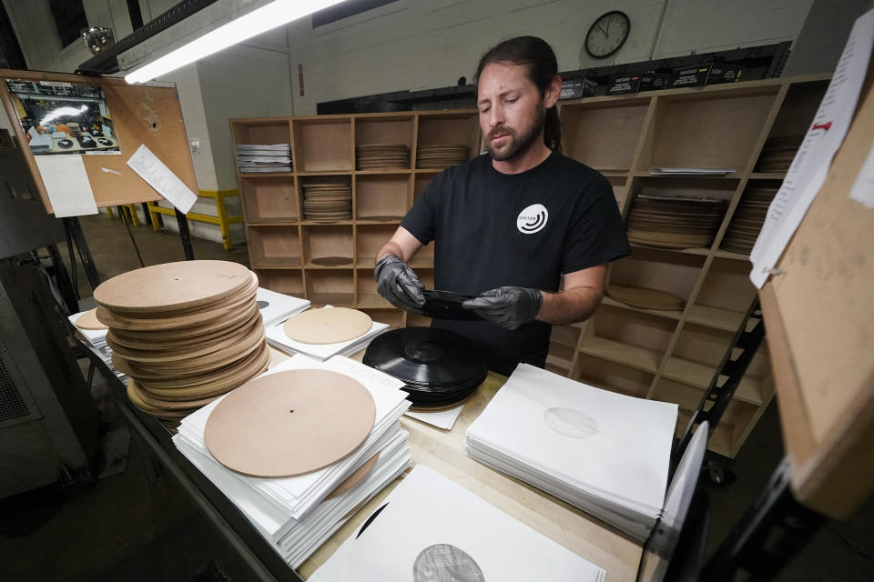 Ricky Riehl inspects finished vinyl records for physical flaws before they are packaged at the United Record Pressing facility Thursday, June 23, 2022, in Nashville, Tenn. (AP Photo/Mark Humphrey)