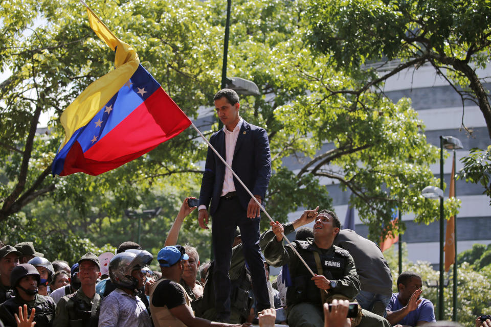 Venezuela's opposition leader and self-proclaimed President Juan Guaidó stands before supporters as he addresses them outside La Carlota military air base in Caracas, Venezuela, Tuesday, April 30, 2019. Guaidó, accompanied by civilian protesters and a small contingent of heavily armed troops, called Tuesday for the military to rise up and oust socialist leader Nicolás Maduro. (AP Photo/Fernando Llano)