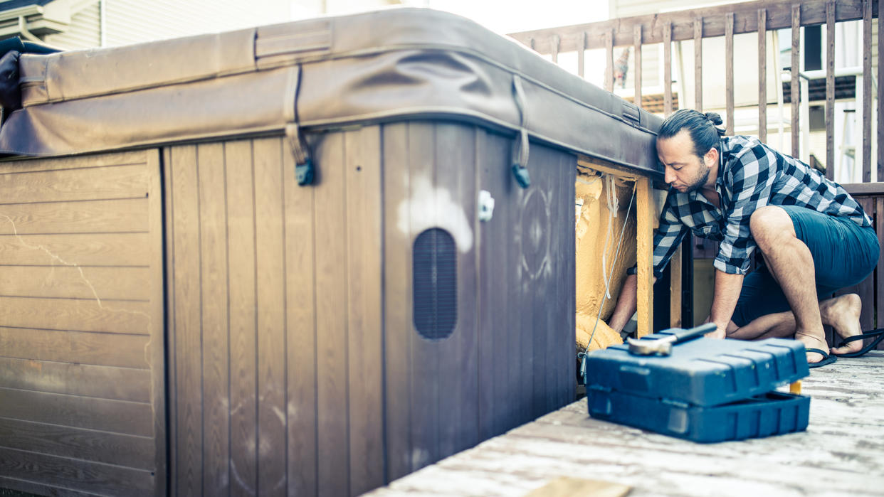  Man installing hot tub on a deck. 