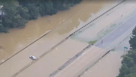 A car sits stranded by floodwaters on Interstate 12 in Livingston Parish, Louisiana, in this still image from video taken August 14, 2016. Louisiana State Police/Handout via REUTERS