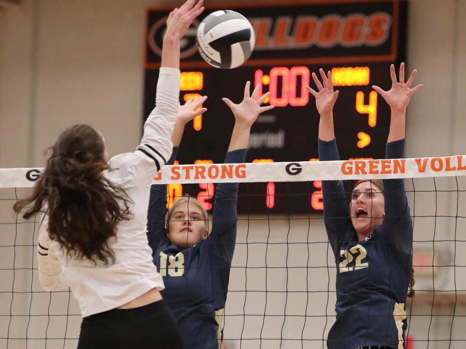 Mia Schindewolf, left, of Green has her shot blocked by Kathleen Jones and Ann Rumler of Hoban during the first set of their match at Green High School Wednesday night. Hoban  won 3 sets to 0. 