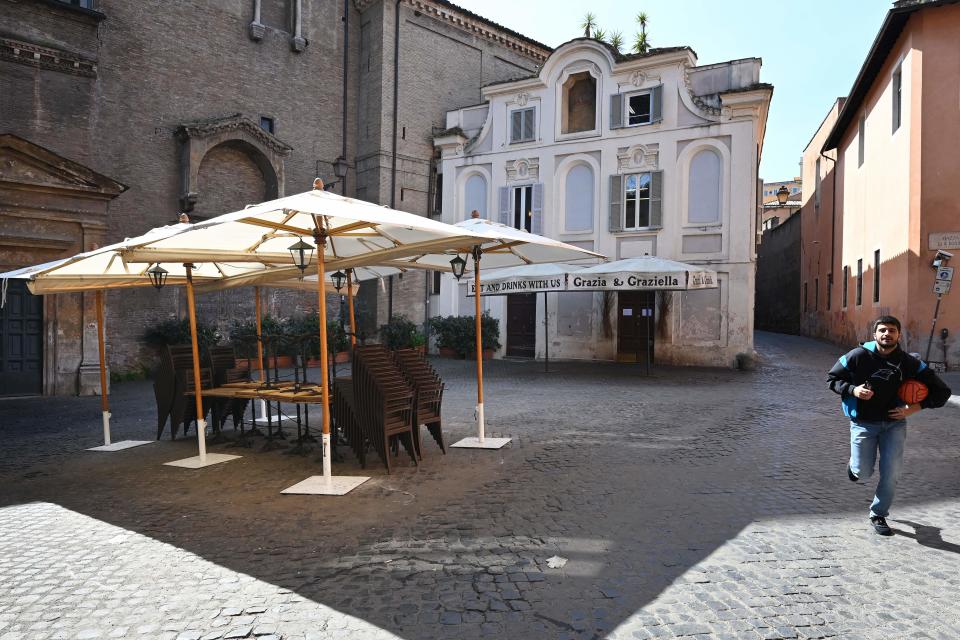 A man runs past an empty restaurant on Piazza di Sant'Egidio in the Trastevere district of Rome on March 10, 2020. (Credit: Alberto Pizzoli/AFP)