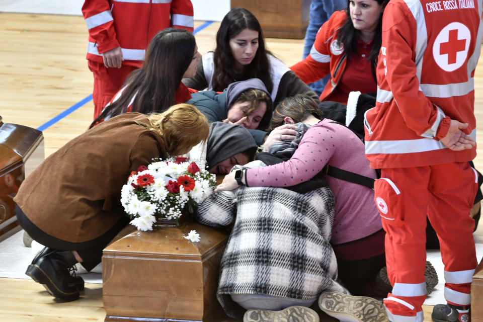 Relatives cry on the coffin of one of the victims of last Sunday's shipwreck at the local sports hall in Crotone, southern Italy, Wednesday, March 1, 2023. At least 67 people, including 14 minors, died when their overcrowded wooden boat slammed into shoals 100 meters (yards) off the shore of Cutro and broke apart early Sunday in rough seas. Eighty people survived, but many more are feared dead since survivors indicated the boat had carried about 170 people when it set off last week from Izmir, Turkey. (AP photo/Giuseppe Pipita)