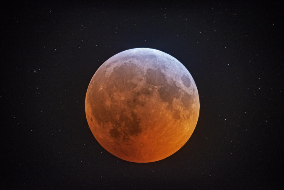 In this photo made with a 12-1/2 inch telescope and provided by Johnny Horne, the totally eclipsed moon glows with a reddish color against the background stars over Stedman, N.C., Monday, Jan. 21, 2019. It was also the year's first supermoon, when a full moon appears a little bigger and brighter thanks to its slightly closer position. During totality, the moon will look red because of sunlight scattering off Earth's atmosphere. That's why an eclipsed moon is sometimes known as a blood moon. In January, the full moon is also sometimes known as the wolf moon or great spirit moon. (Johnny Horne via AP)
