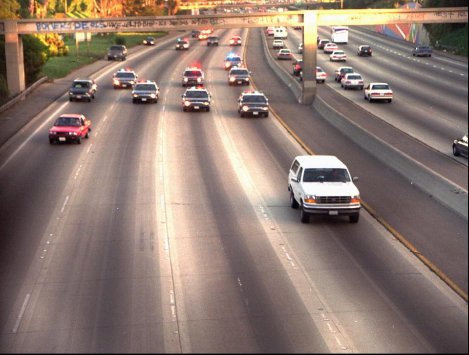 A white Ford Bronco, driven by Al Cowlings and carrying O.J. Simpson, is trailed by police cars as it travels on a southern California freeway on June 17, 1994, in Los Angeles. Cowlings and Simpson led authorities on a chase after Simpson was charged with two counts of murder in the deaths of his ex-wife and her friend. (AP Photo/Joseph Villarin)