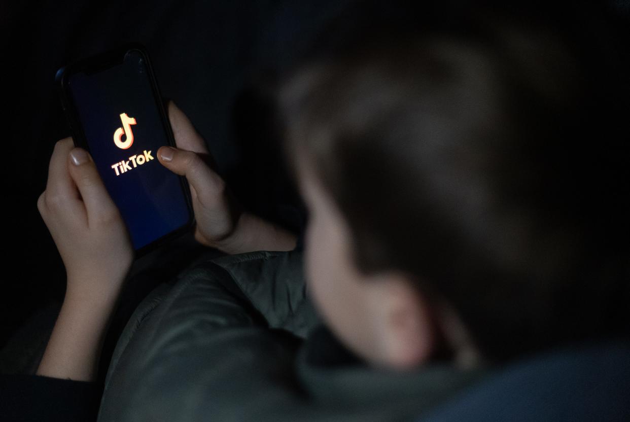 A 12-year-old boy looks at a smartphone screen displaying the TikTok logo on March 10, 2024 in Bath, England.