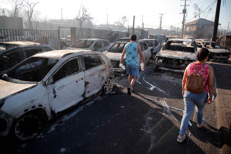 Algunos residentes caminan entre los vehículos quemados en un barrio de Viña del Mar