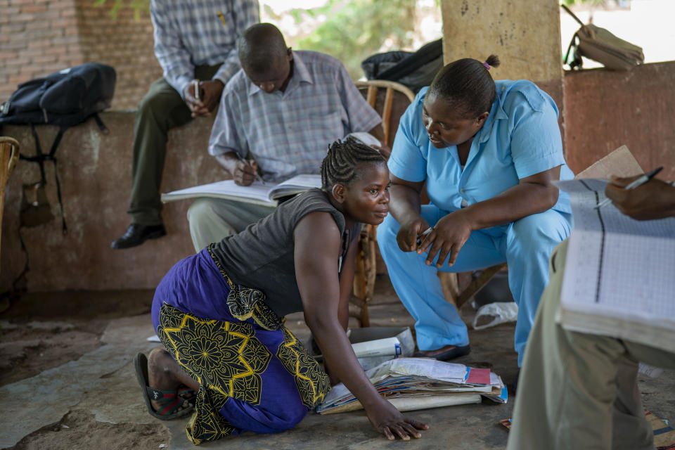 In this photo taken Wednesday Dec. 11, 2019, Dorigha Ephrem listens to health officials in the Malawi village of Tomali. Ephrem's 5 month old daughter Grace became a test subject for the world's first vaccine against malaria. Parents in Malawi, as well as Kenya and Ghana, are being asked to put faith in a series of injections that are only about 40% effective. (AP Photo/Jerome Delay)