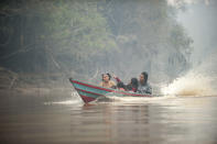 Villagers ride a boat on a river near a forest blanketed by haze from forest fires near Kaja Island, Central Kalimantan, Indonesia, Thursday, Sept. 19, 2019. Indonesia's fires are an annual problem that strains relations with neighboring countries. The smoke from the fires has blanketed parts of Indonesia, Singapore, Malaysia and southern Thailand in a noxious haze. (AP Photo/Fauzy Chaniago)