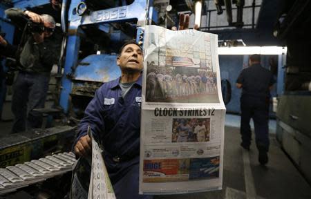 Printer Jose Lomeli (C) checks the first copy of the inaugural Los Angeles Register newspaper as it comes off the press in Santa Ana, California April 16, 2014. REUTERS/Lucy Nicholson