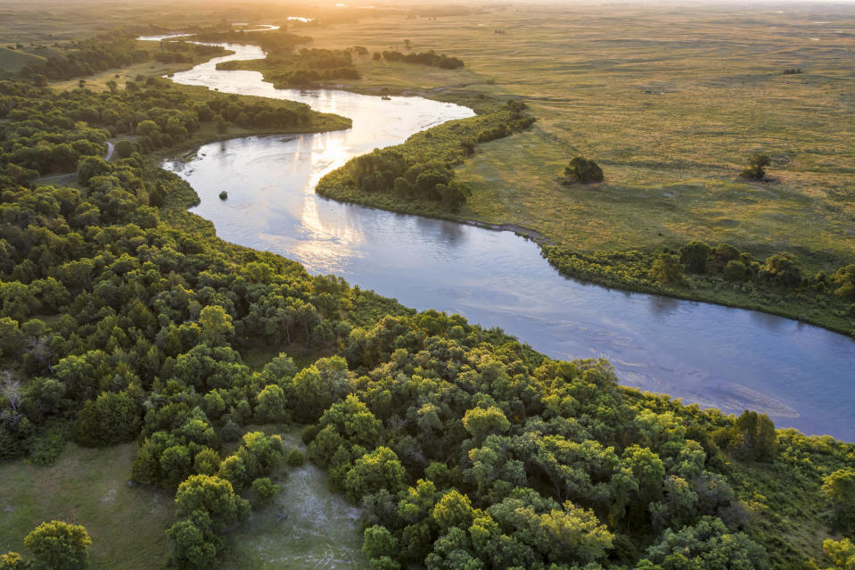 sunrise over Dismal River meandering through Nebraska Sandhills at Nebraska National Forest, aerial view of summer scenery