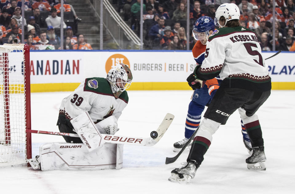 Arizona Coyotes goalie Connor Ingram (39) makes the save as Edmonton Oilers' Zach Hyman (18) and Coyotes' Michael Kesselring (5) battle in front during the second period of an NHL hockey game in Edmonton, Alberta, Wednesday, March 22, 2023. (Jason Franson/The Canadian Press via AP)